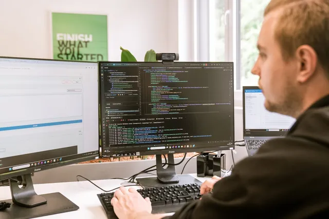 Entwickler prüft Code an mehreren Monitoren